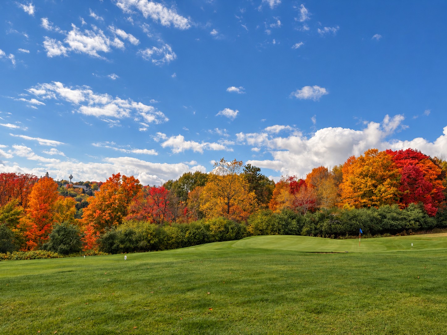 Autumn trees around the green at Crystal View with Crystal Falls in the background